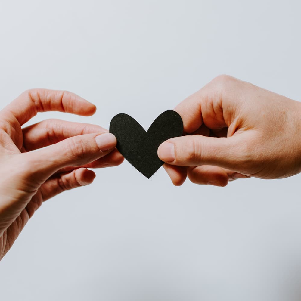 Hands sharing a paper heart
